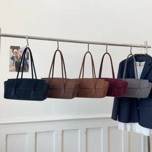 Détail de cinq sacs cabas en daim colorés avec doubles bandoulières sur un support