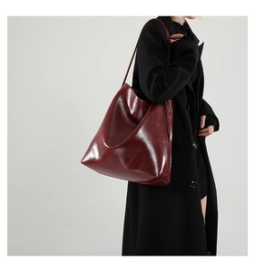 Detailansicht der burgunderfarbenen Leder-Tote-Bag mit Glanzeffekt zum schwarzen Mantel