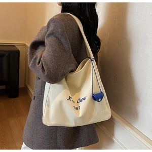 Détail du sac cabas en toile crème avec broderie bleue et pochette de rangement assortie