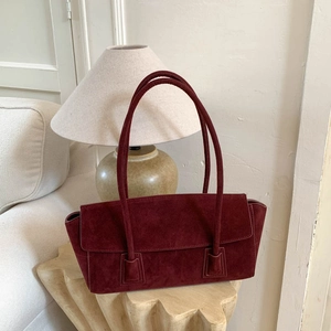 Vue détaillée d'un sac cabas en daim bordeaux posé sur une table en bois clair