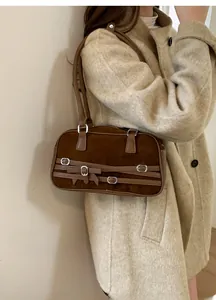 Brown suede shoulder bag detail showing vintage straps and silver buckles on a coat
