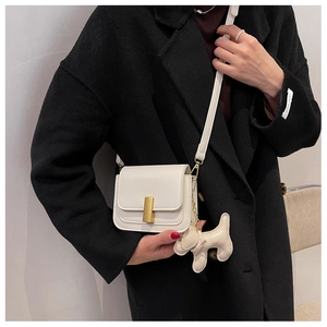 Détail du sac bandoulière crème avec fermoir doré et accessoire de charme chien en cuir