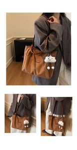 Close-up of brown suede tote bag with woven leather handle and cloud plush charm
