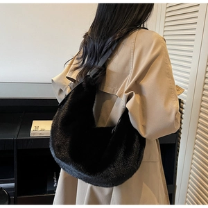 Close-up of black plush faux fur shoulder bag with leather strap and glossy texture