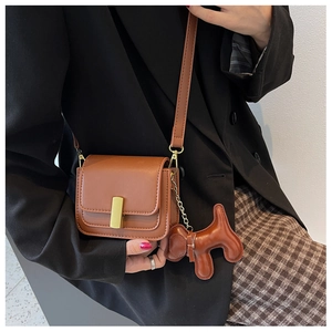 Détail du sac en cuir caramel avec fermoir doré rectangulaire et breloque chien