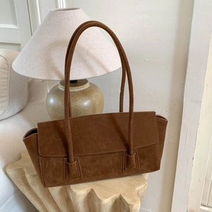 Détail du sac à épaule en daim marron avec rabat minimaliste et texture mate et douce