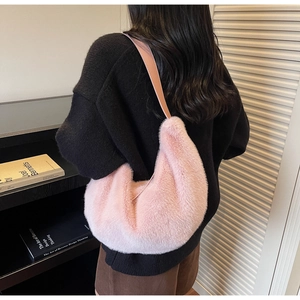 Pink plush crescent shoulder bag shown on shoulder in a cozy minimalist interior