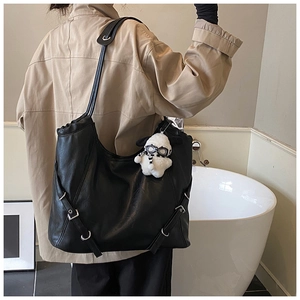 Detail of black PU leather tote bag with lychee texture and plush pendant accessory