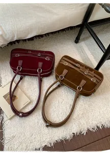 Detail of vintage suede bowling bags in burgundy and brown with metallic buckles