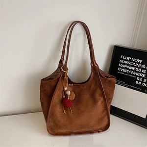 Vue détaillée du sac hobo en daim marron avec pompons colorés et bordures en cuir