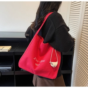 Détail d'un grand sac cabas en toile rouge avec lettrage blanc et petit pendentif