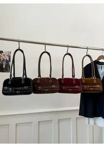 Detail of four retro suede boston bags with bow accents in black, brown, red, and tan