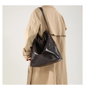 Detail einer dunkelbraunen Leder-Shopper-Tasche getragen zum hellen Trenchcoat
