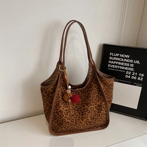 Détail du sac cabas en daim léopard avec anses en cuir et breloque pompon décorative