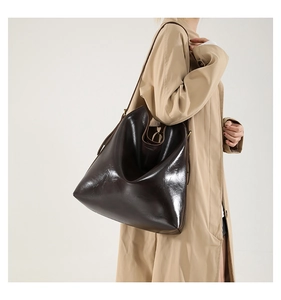 Detailansicht der glänzenden dunkelbraunen Leder-Shopper-Tasche am Model mit breitem Riemen