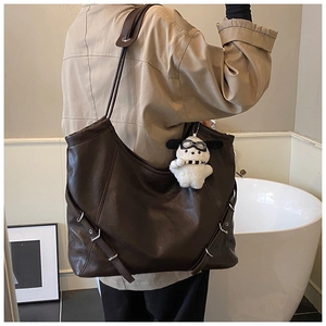 Detail of vintage brown tote bag with leather straps, side buckles, and cute dog charm