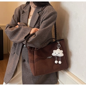 Close-up of brown suede tote bag with woven handles and a cute white cloud plush pendant