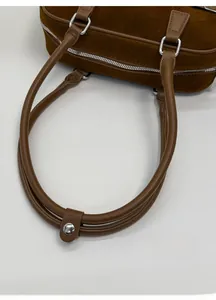 Detail view of the brown suede bowling bag with high-quality leather handles and silver hardware