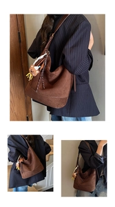 Detail of a large brown suede tote bag with a plush bear charm and woven drawstring