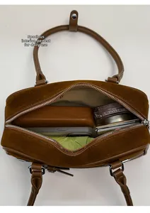 Detailed top view of large capacity brown suede bowling bag with daily essentials inside