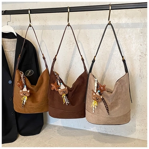 Detailed close-up of large suede bucket bags in brown and khaki with cute teddy charms