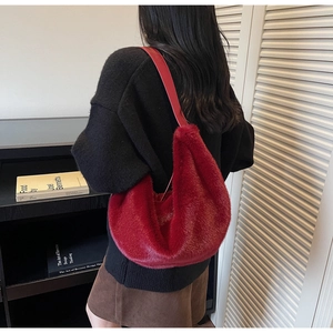 Close-up of deep red plush hobo bag with soft faux fur texture and smooth strap