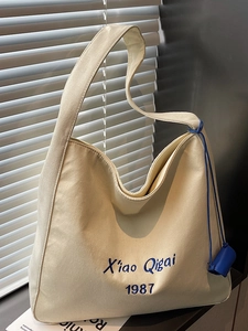 Sac fourre-tout minimaliste en toile beige avec broderie bleue et pendentif pour femmes