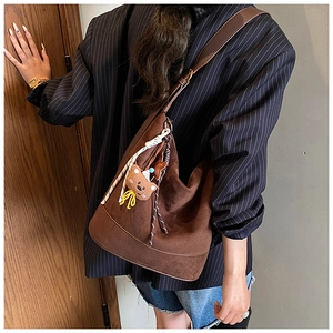 Detail of a brown suede bucket bag with cute bear charm and colorful tassels