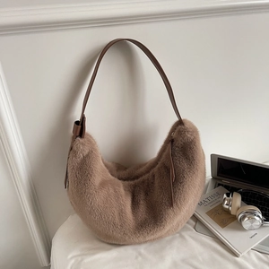 Close-up of brown plush crescent bag with PU strap on a minimalist white aesthetic setup