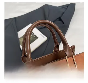 Gros plan du sac à main en daim marron avec anneaux métalliques dorés et poignée en cuir