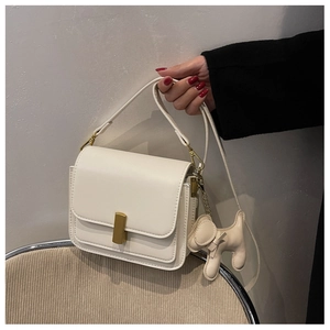 Vue détaillée du sac à main crème avec fermoir doré et pendentif en forme de chien