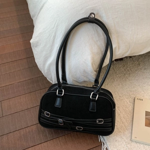 Detail of black suede shoulder bag with triple silver buckles and zip closure on floor