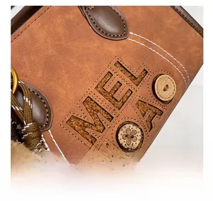 Gros plan d'un sac en daim marron avec logo brodé et détails de cordes tressées
