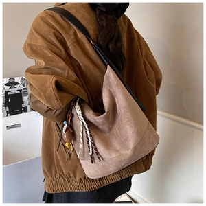 Detailed macro view of khaki suede tote bag with woven pendant and plush doll charm decor