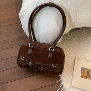 Detail of dark brown retro suede shoulder bag with decorative belt and bow detail