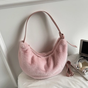 Detailed view of a pink plush crescent bag with PU strap and artistic lifestyle props