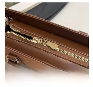 Détail du sac à main en cuir marron foncé avec coutures en daim et fermeture dorée
