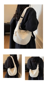 Detailed close-up of a minimalist cream canvas hobo bag with adjustable strap and zipper