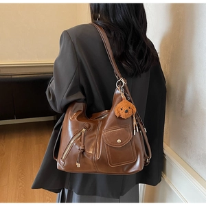 Detail of a large brown oil-wax leather tote with golden snap pocket and dog pendant