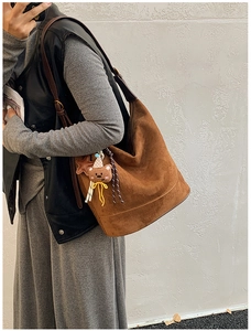Close-up of caramel suede bucket bag with decorative bear charm and fine matte texture