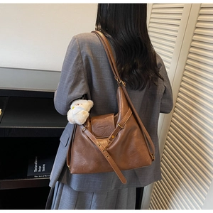 Detail of vintage dark brown tote with plush bear charm on elegant grey blazer suit