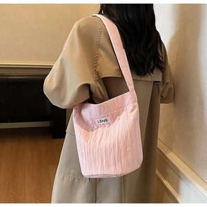 Pink pleated tote bag with LOVE label shown on model wearing a beige trench coat