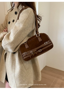 Detailed close-up of dark brown suede bowling bag with buckle and bow details