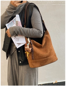 Detail of caramel brown suede tote bag with plush bear charm and leather strap