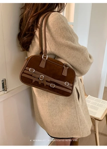 Detail of a brown suede bowling bag featuring a vintage metal buckle and chic bow accent