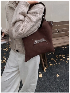 Detail view of dark brown suede tote bag featuring silver punk studs and metal accents