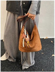 Close-up of brown suede hobo bag featuring leather star charm and cute bear tassel detail