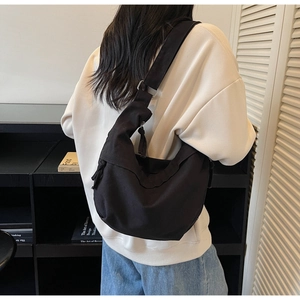 Detail of adjustable wide shoulder strap on minimalist black crescent crossbody bag