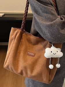 Brown suede tote bag with woven handles and plush cloud charm on model's shoulder
