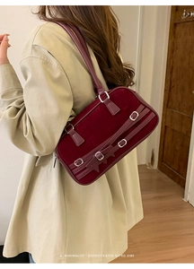 Detailed side view of deep wine red suede shoulder bag with retro buckles and bow accent
